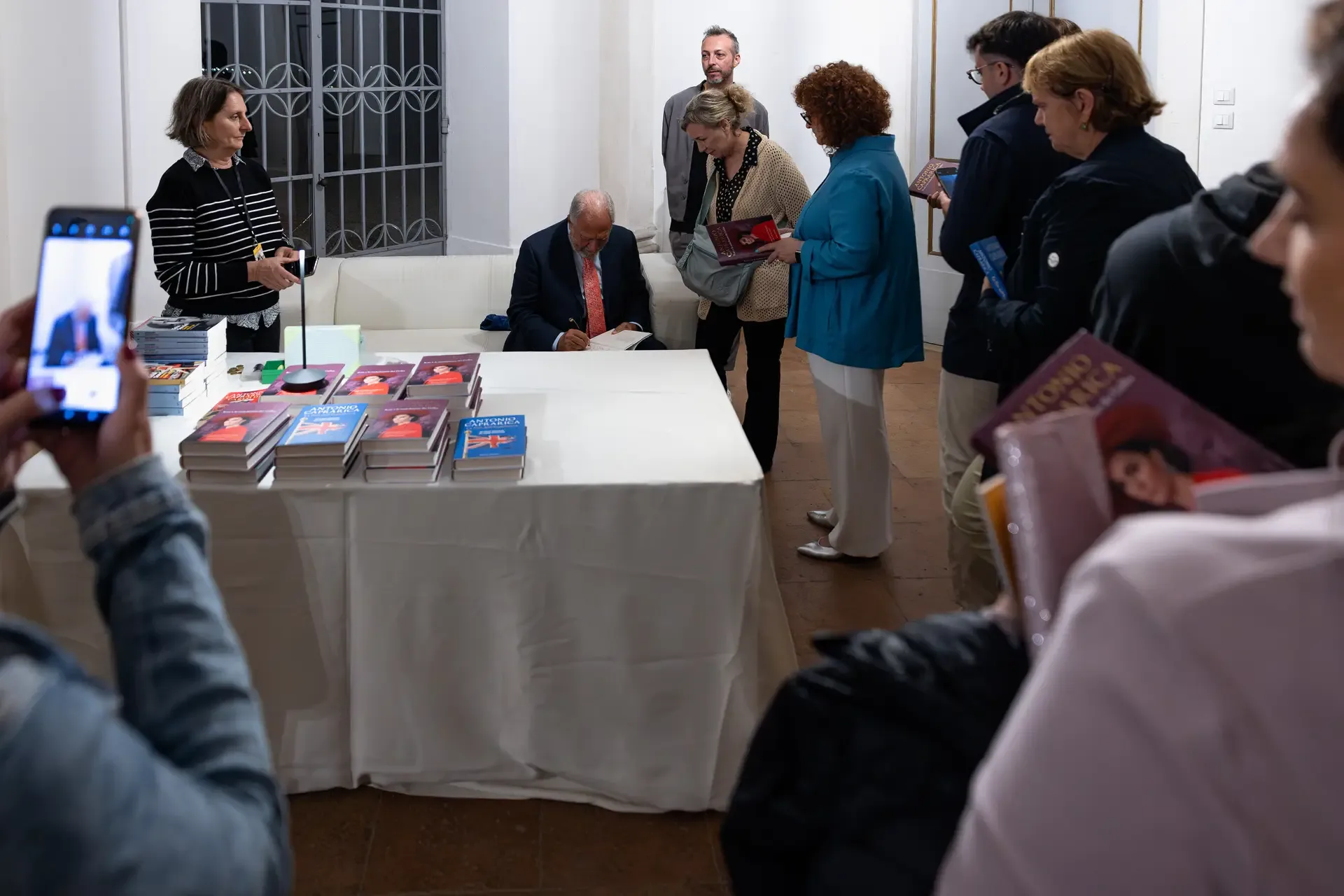 Lunga fila di lettori al Giardino di Pojega per il firmacopie di Antonio Caprarica durante il Festival della Bellezza 2025